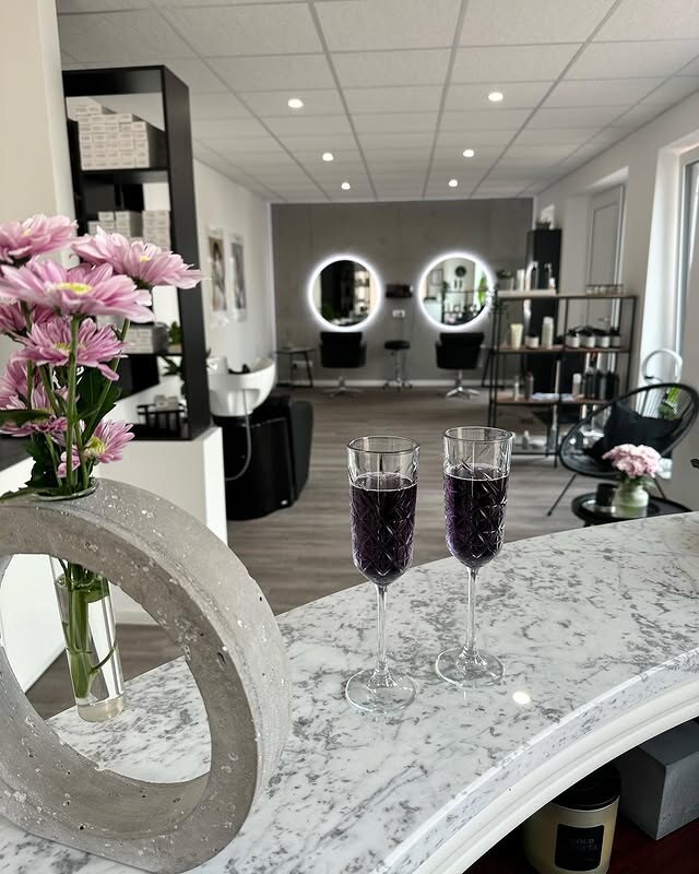 Empfangstresen aus Marmor mit Blumen, dahinter der Salonraum mit zwei Leuchtspiegeln